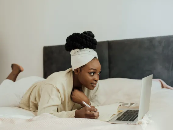 person lying on a bed using a laptop