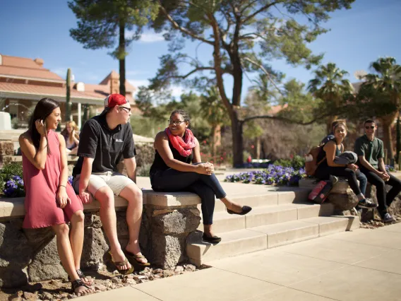 group of people sitting on a bench in front of a fountain