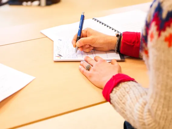 close up of a person's hands writing in a notebook