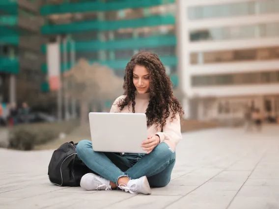 person sitting on the ground outside using a laptop