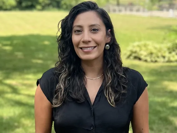 headshot of a person standing outside with grass and trees in the background