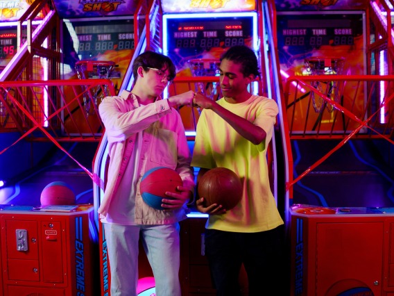 two friends fist-bumping while playing arcade games