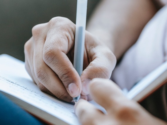 close-up of a person's hands while writing in a journal