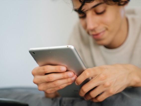 person looking down toward a tablet and smiling