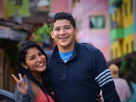 Two people smiling and showing peace sign. 