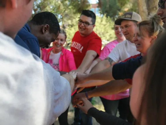 group of students touching hands outdoors