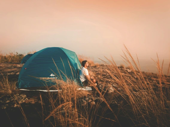 person sitting on a mountain with a tent in the background