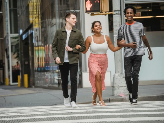 three people walking across the street arm in arm