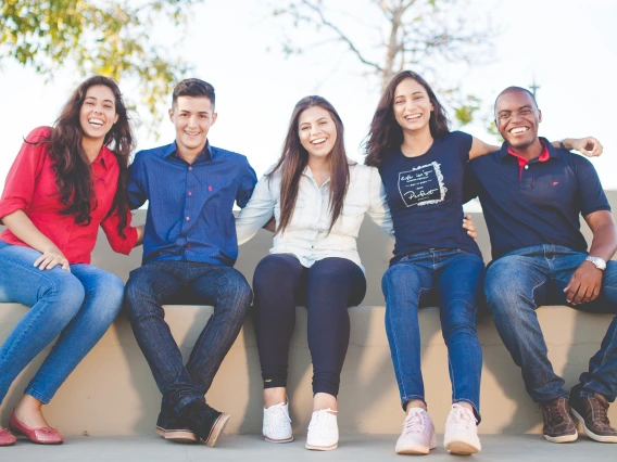 Group of 5 students sitting together and smiling