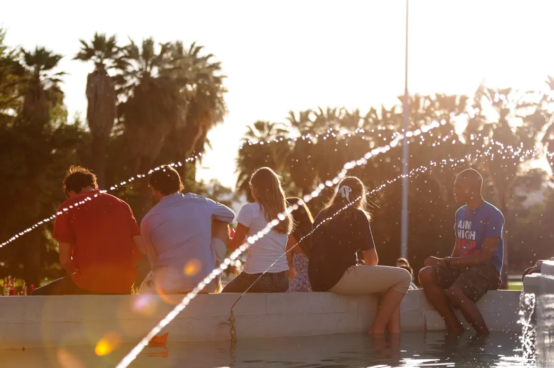 group of students sitting by a fountain and talking