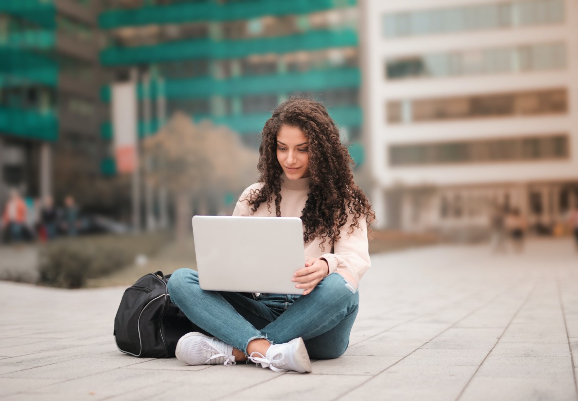 person sitting on the ground outside using a laptop