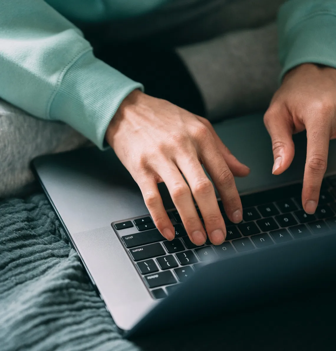 view of two hands typing on a laptop computer