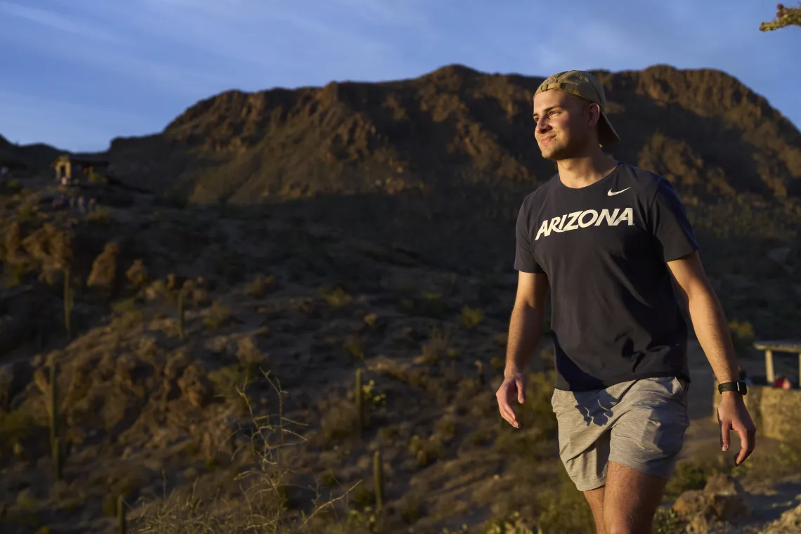 Male student walking outside on a trail