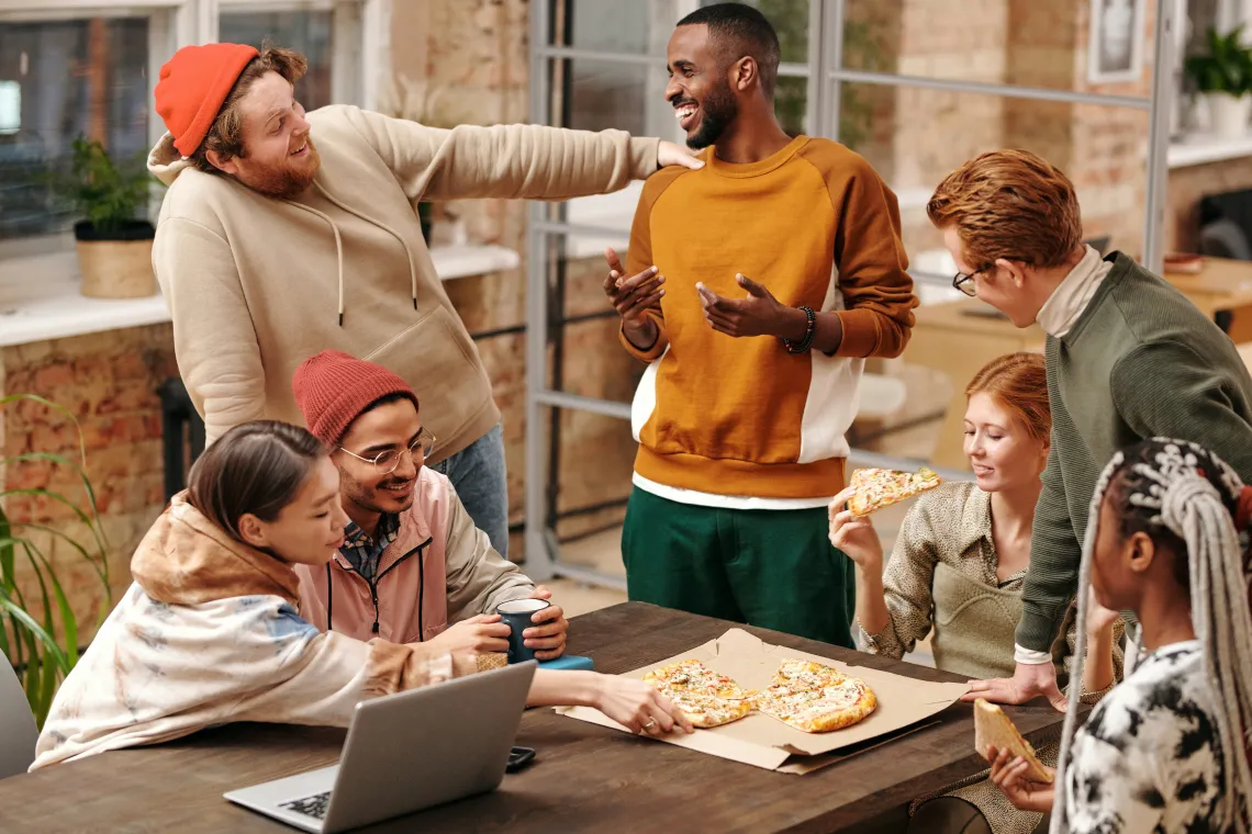 Group of friends sharing a pizza outside laughin