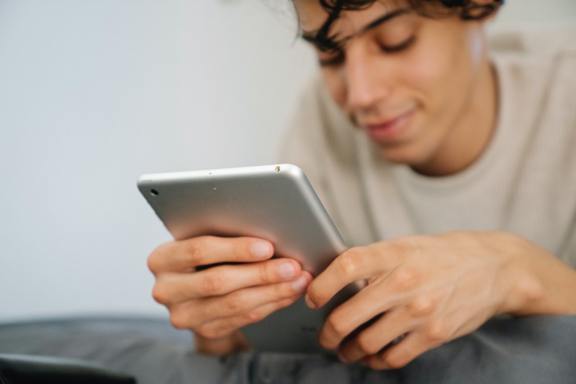 person looking down toward a tablet and smiling