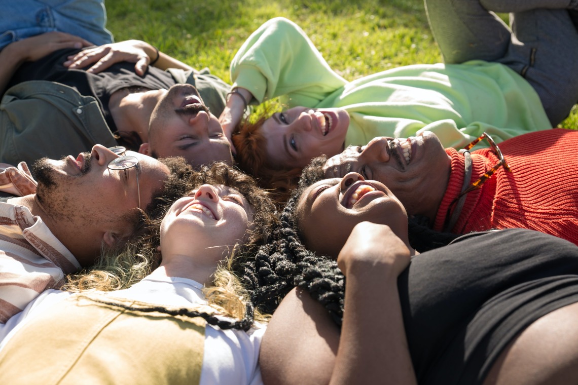 group of people lying in a circle in the grass