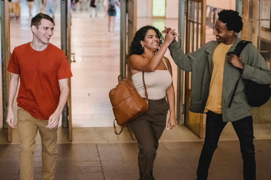 three people wearing backpacks walking through doors in a public space