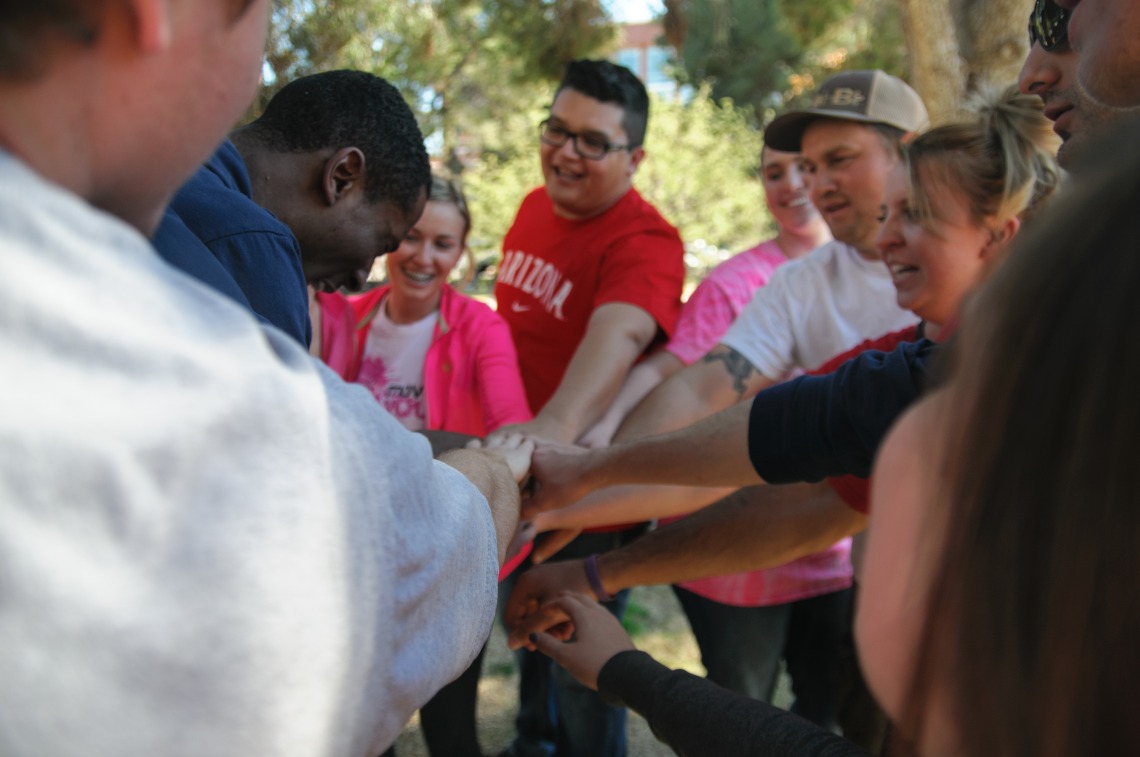 group of students touching hands outdoors