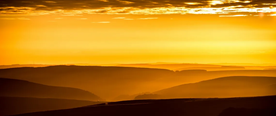 yellow sky behind the silhouette of mountains