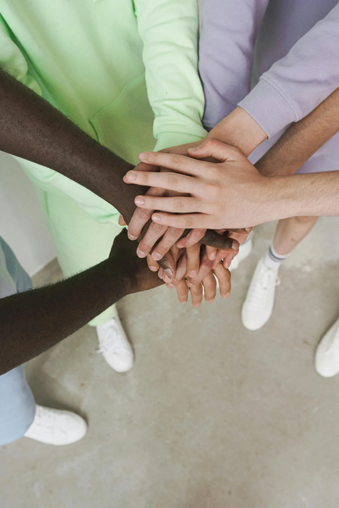 group of people with their hands together in a circle seen from above