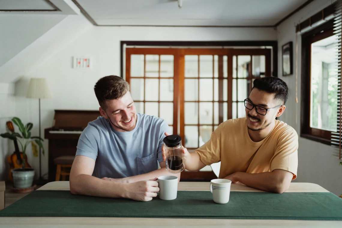 two people sitting at a table with cups of coffee
