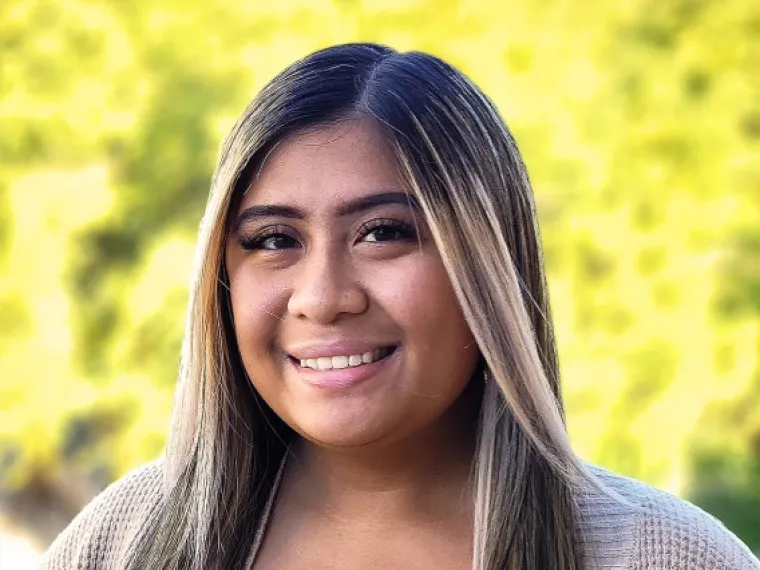 headshot of a person with trees in the background