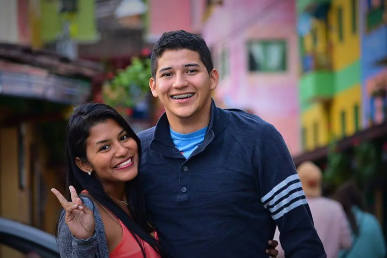 Two people smiling and showing peace sign. 