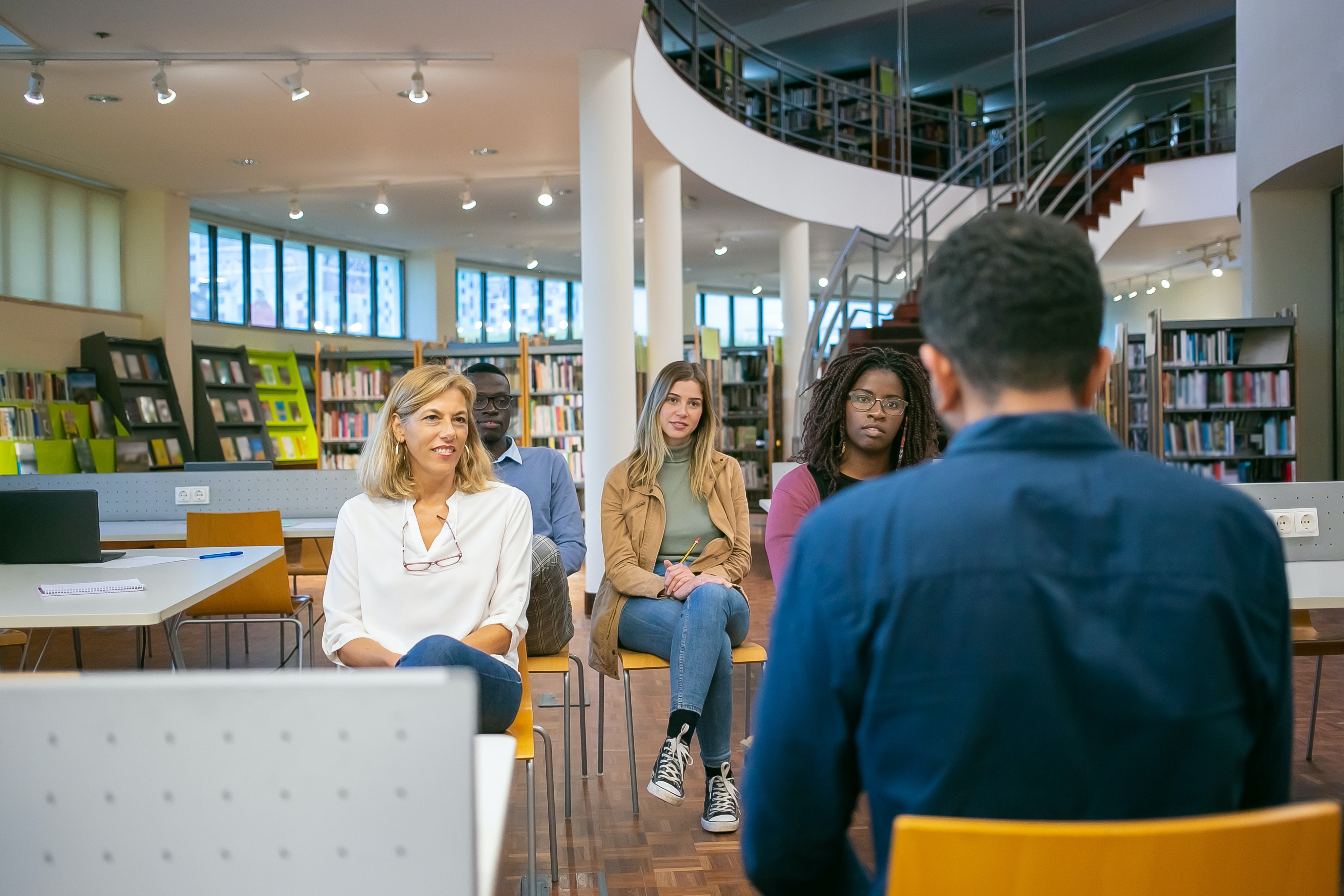 a small group of students listening to a presentation in a library