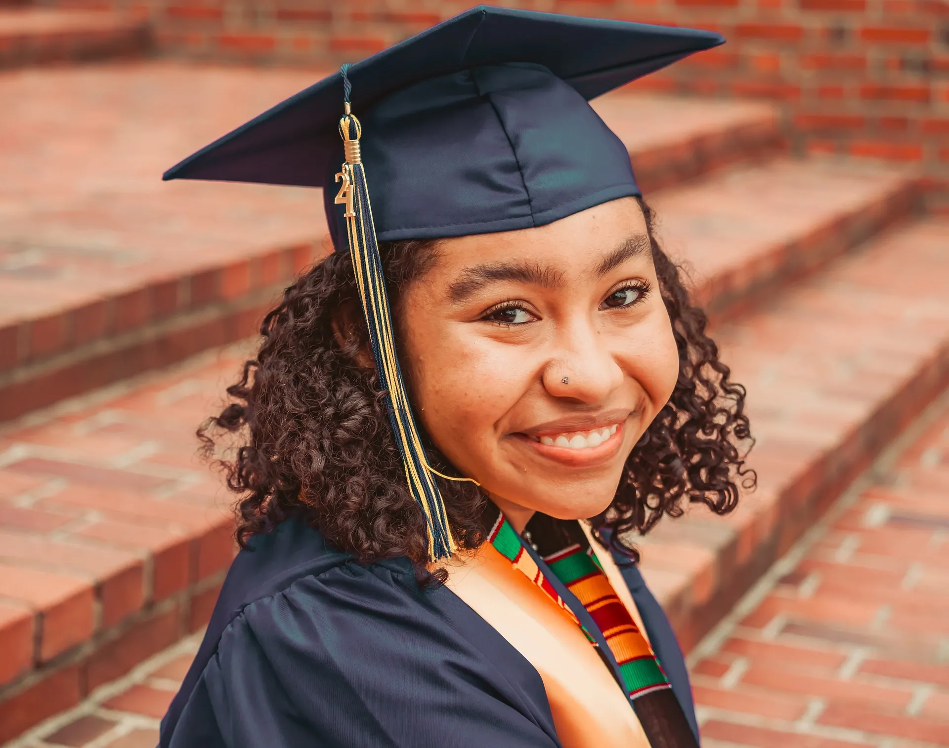 Women in graduation gown sitting on brick steps and smiling