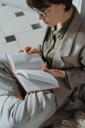 person sitting on the floor and reading a book