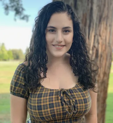 headshot of a woman standing in front of a tree